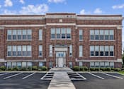 Thumbnail 1 of 17 - A large red brick building with a white door and windows.