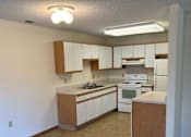 Thumbnail 4 of 13 - A kitchen with white appliances and wooden cabinets.