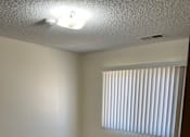 Thumbnail 12 of 13 - A room with a carpeted floor and a window with blinds.