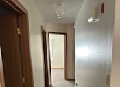 Thumbnail 10 of 13 - A hallway with a carpeted floor and a white wall.
