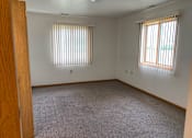 Thumbnail 7 of 15 - A room with a carpeted floor and two windows with blinds.