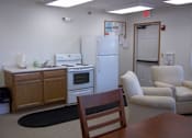 Thumbnail 3 of 15 - A kitchen with a refrigerator, oven, and a table with a chair.