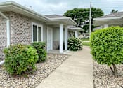Thumbnail 1 of 15 - A residential area with a house, bushes, and a gravel path.