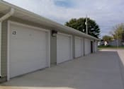 Thumbnail 4 of 10 - A row of white garage doors are closed and numbered 12.