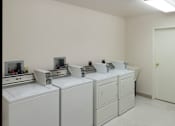 Thumbnail 10 of 10 - A white room with a row of washing machines.