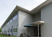 Thumbnail 1 of 10 - A house with a grey siding and a white roof.