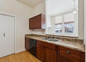 Thumbnail 7 of 27 - A kitchen with brown cabinets and a black dishwasher.