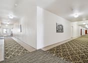 Thumbnail 15 of 27 - A hallway with a carpeted floor and a picture on the wall.