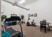 Thumbnail 16 of 27 - A room with a treadmill, exercise bike, and other workout equipment.