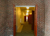 Thumbnail 17 of 27 - A hallway with a brick wall and a carpeted floor.
