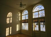 Thumbnail 13 of 27 - A room with a ceiling fan and large windows letting in sunlight.