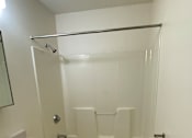 Thumbnail 5 of 6 - A white bathroom with a glass shower door and a white toilet.