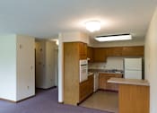 Thumbnail 4 of 12 - A kitchen with wooden cabinets and a white refrigerator.