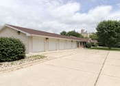 Thumbnail 12 of 12 - A large garage with a brown roof is surrounded by a concrete driveway.