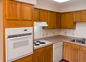 Thumbnail 5 of 12 - A kitchen with wooden cabinets and a white oven.