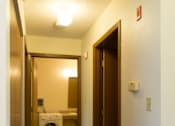 Thumbnail 11 of 12 - A hallway with a washing machine in the doorway.