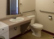Thumbnail 9 of 12 - A bathroom with a toilet, sink, mirror, and washer.