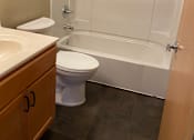 Thumbnail 12 of 13 - A white toilet is next to a white bathtub in a bathroom.
