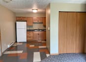 Thumbnail 6 of 13 - A kitchen with a white fridge and wooden cabinets.