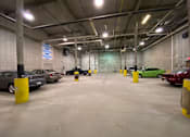 Thumbnail 16 of 17 - A parking garage with cars parked and yellow bollards.