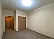 Thumbnail 12 of 17 - A room with two doors and carpeted floor.