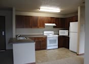 Thumbnail 2 of 12 - A kitchen with white appliances and brown cabinets.