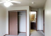 Thumbnail 9 of 12 - A room with a ceiling fan and a door leading to a kitchen.