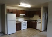 Thumbnail 3 of 12 - A kitchen with white appliances and brown cabinets.