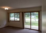 Thumbnail 3 of 6 - A room with a sliding glass door leading to a backyard.