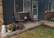 Thumbnail 3 of 12 - A house with a blue siding and a porch with two chairs and a table.