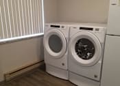Thumbnail 12 of 12 - Two front loading washing machines in a laundry room.