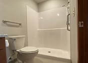 Thumbnail 10 of 12 - A white toilet sits in a bathroom next to a bathtub.