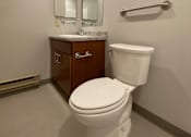 Thumbnail 9 of 12 - A white toilet in a bathroom with a wooden cabinet and mirror.