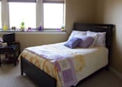 Thumbnail 9 of 11 - A bedroom with a bed, a desk, and a window.