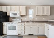 Thumbnail 9 of 25 - A kitchen with white appliances and cabinets.
