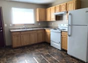 Thumbnail 4 of 7 - A kitchen with a white refrigerator, white stove, and wooden cabinets.