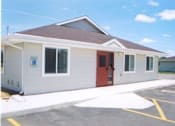Thumbnail 3 of 13 - A small building with a red door and a parking lot in front.