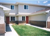 Thumbnail 2 of 13 - A house with a red door and a green lawn.