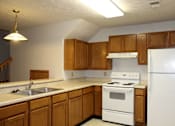 Thumbnail 5 of 13 - A kitchen with white appliances and wooden cabinets.