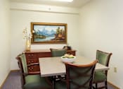 Thumbnail 5 of 12 - A painting of a mountain scene is on the wall above a table with chairs around it.