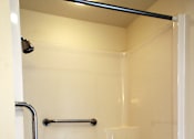 Thumbnail 11 of 12 - A white shower stall with a black grab bar.