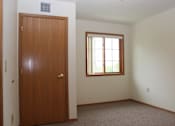Thumbnail 8 of 12 - A room with a brown door and a window with white blinds.