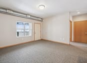 Thumbnail 2 of 30 - A room with a window, two doors, and a carpeted floor.