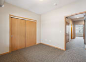Thumbnail 14 of 30 - A room with a carpeted floor and a wooden door.