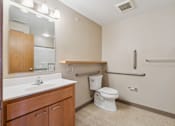 Thumbnail 17 of 30 - A bathroom with a toilet, sink, and mirror.