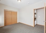 Thumbnail 11 of 30 - A room with a carpeted floor and a wooden door.
