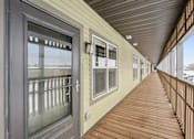 Thumbnail 27 of 30 - A long wooden balcony with a sliding door and windows.