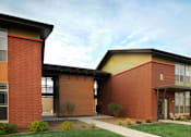 Thumbnail 23 of 30 - A red brick building with a yellow roof and a covered walkway.