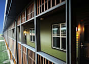 Thumbnail 24 of 30 - A building with a green siding and a black door.