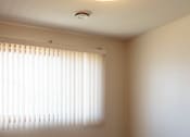 Thumbnail 12 of 13 - A room with a carpeted floor and a window with blinds.